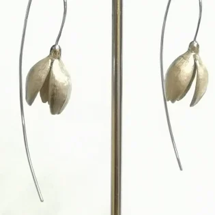 silver snowdrop earrings hanging from stand