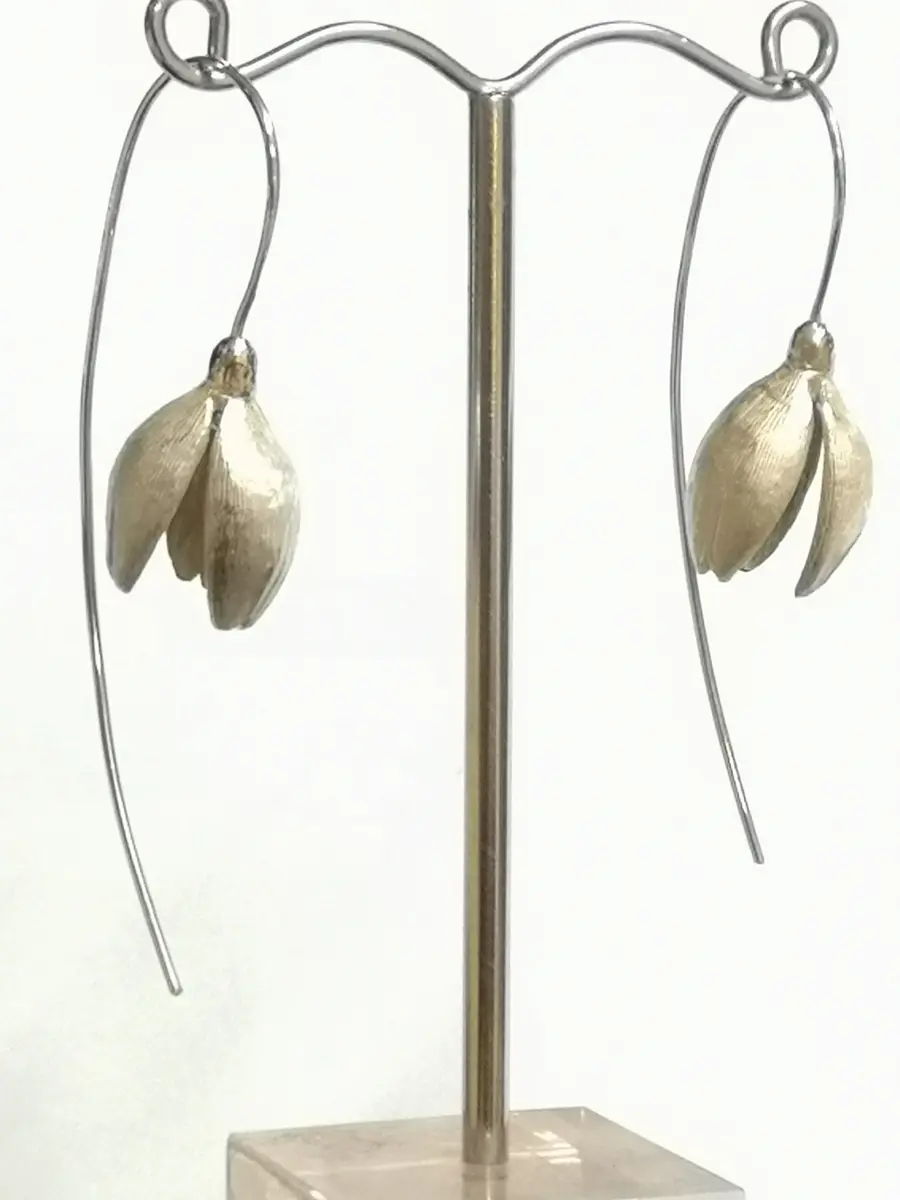 silver snowdrop earrings hanging from stand
