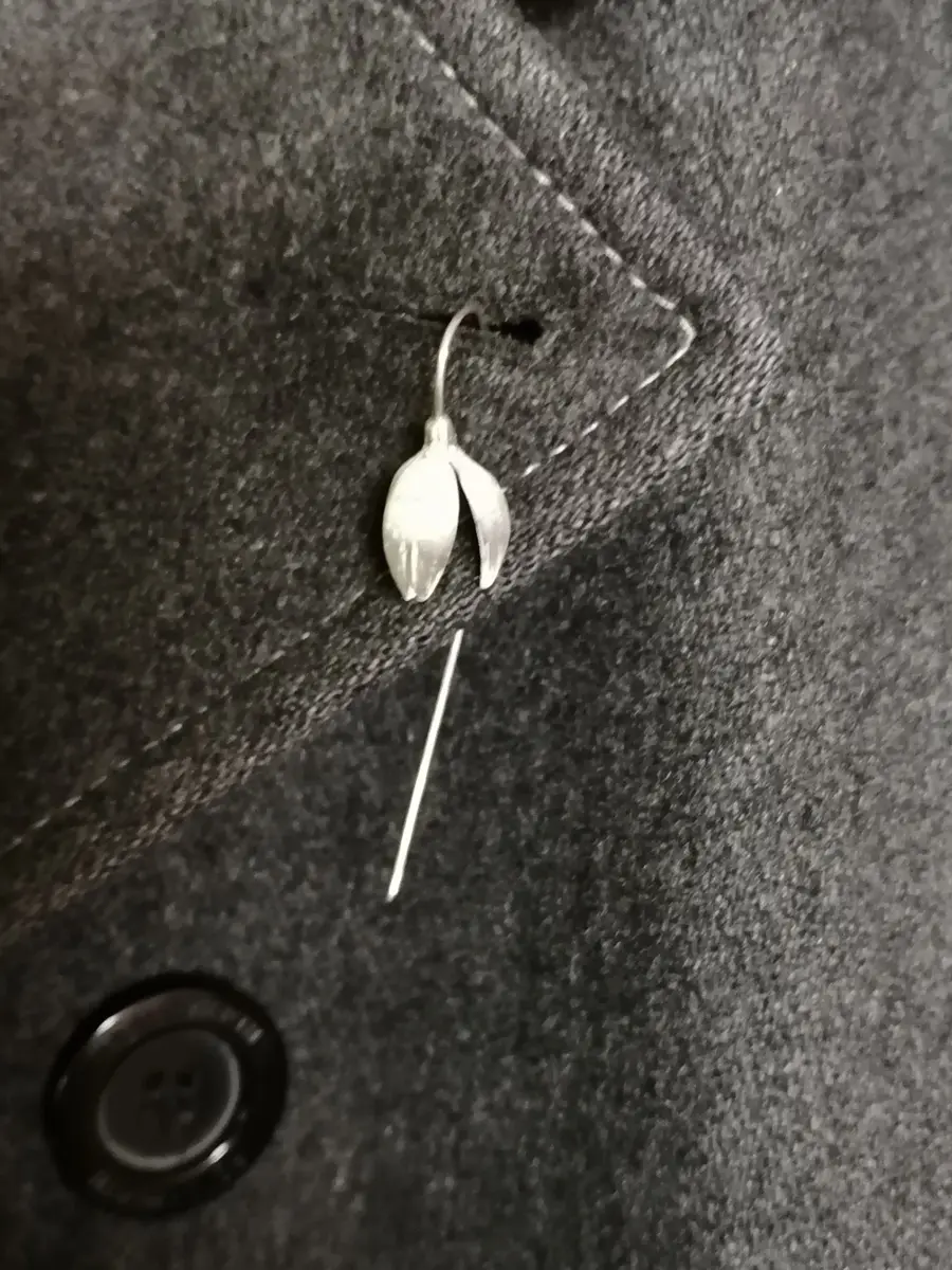 Silver snowdrop pin on a grey coat