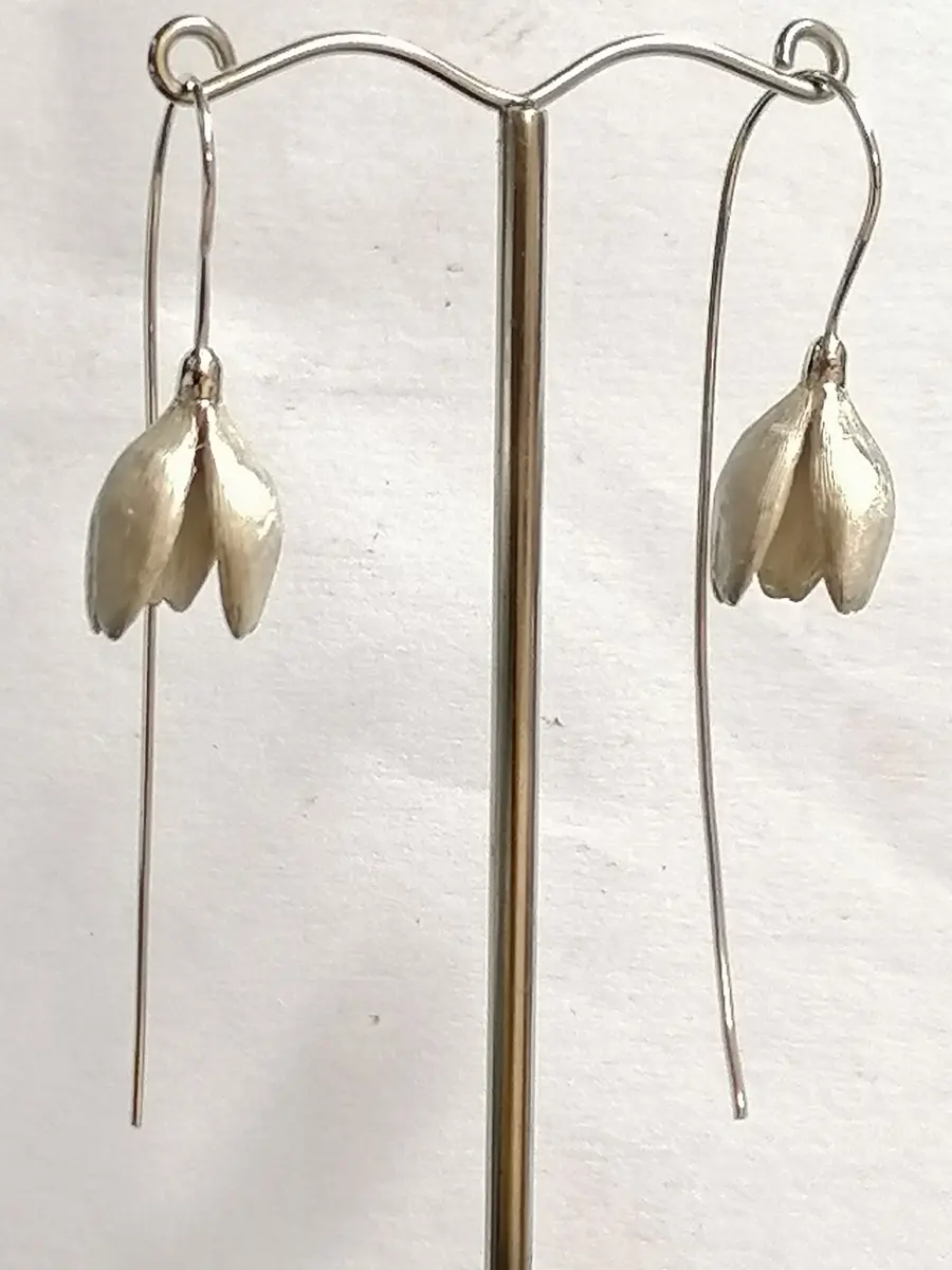 realistic silver snowdrop earrings hanging from stand